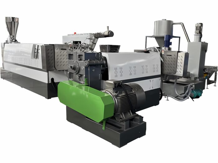 a plastic HDPE (High-Density Polyethylene) and PP (Polypropylene) regrind flakes pelletizing machine. This machinery is designed to melt and reform plastic flakes into pellets, which are then used as raw materials in various manufacturing processes. The equipment features multiple components including a feeding system, an extruder to melt the plastic, and a pelletizing unit where the melted plastic is cut into uniform pellets. The machine is predominantly in shades of gray and silver, with a distinctive green component that likely houses part of the mechanical or processing equipment. This type of machine is crucial in recycling operations, allowing for the efficient reuse of plastic materials and contributing to sustainable manufacturing practices.